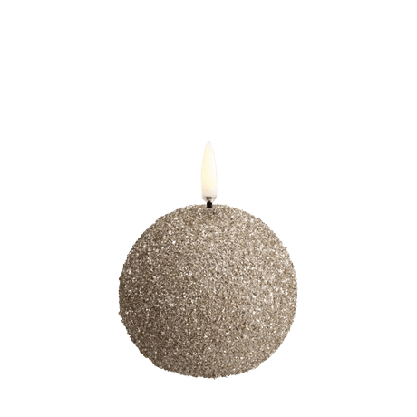 Uyuni LED sneboldlys i champagnefarvet glimmerfinish med livagtig flamme – rund form som en snebold, fotograferet i varm, stemningsfuld belysning.