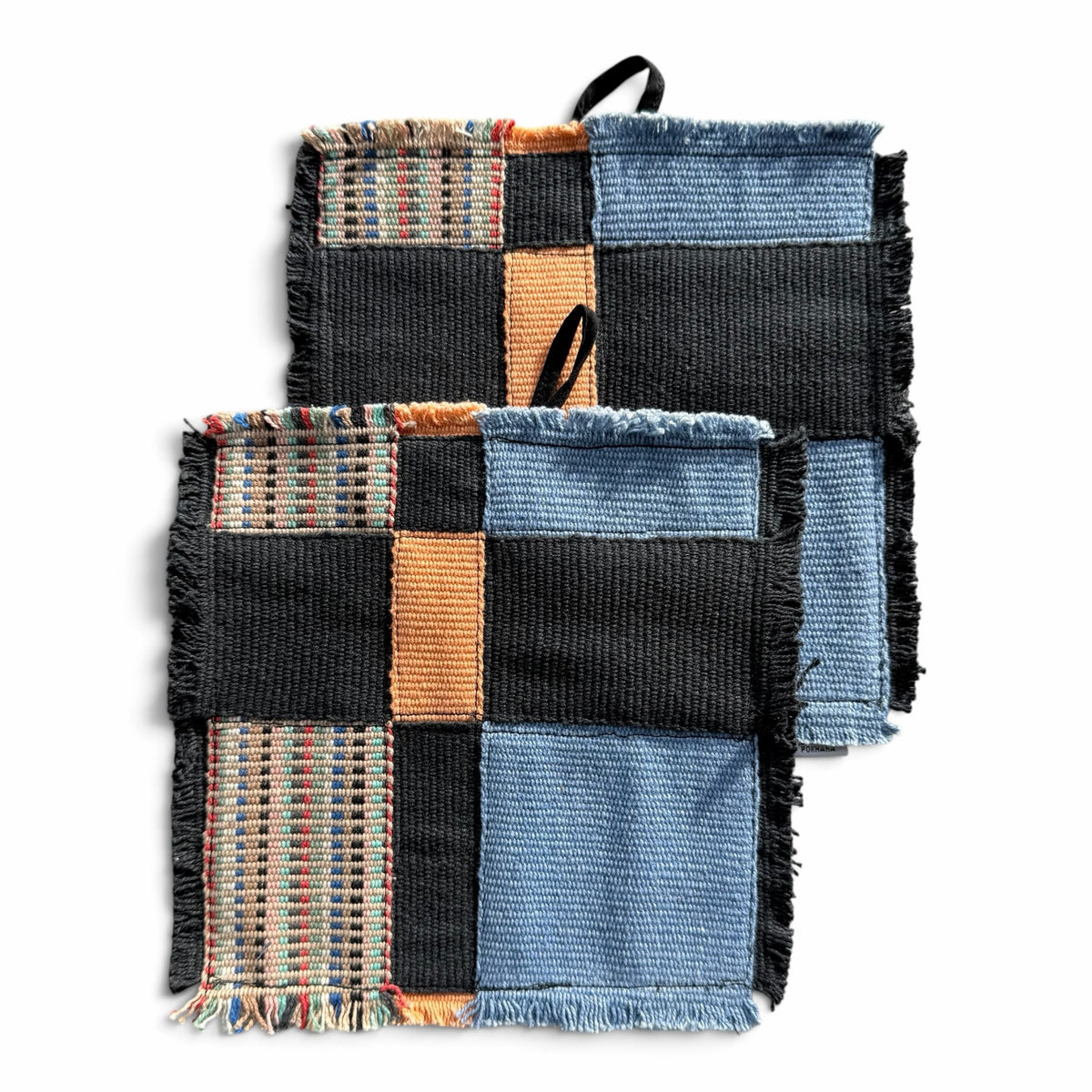 himmerli håndvævede grydelapper i patchwork-design med sorte, denimblå og jordfarvede teksturer samt rå frynsekanter.