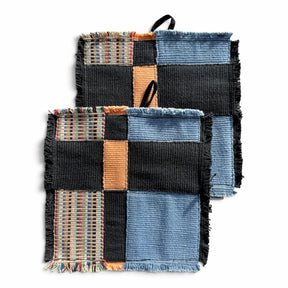 himmerli håndvævede grydelapper i patchwork-design med sorte, denimblå og jordfarvede teksturer samt rå frynsekanter.