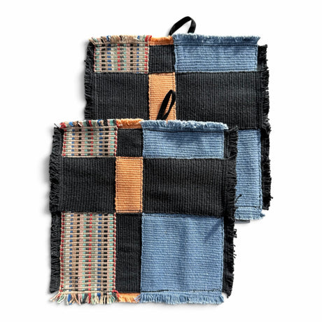 himmerli håndvævede grydelapper i patchwork-design med sorte, denimblå og jordfarvede teksturer samt rå frynsekanter.