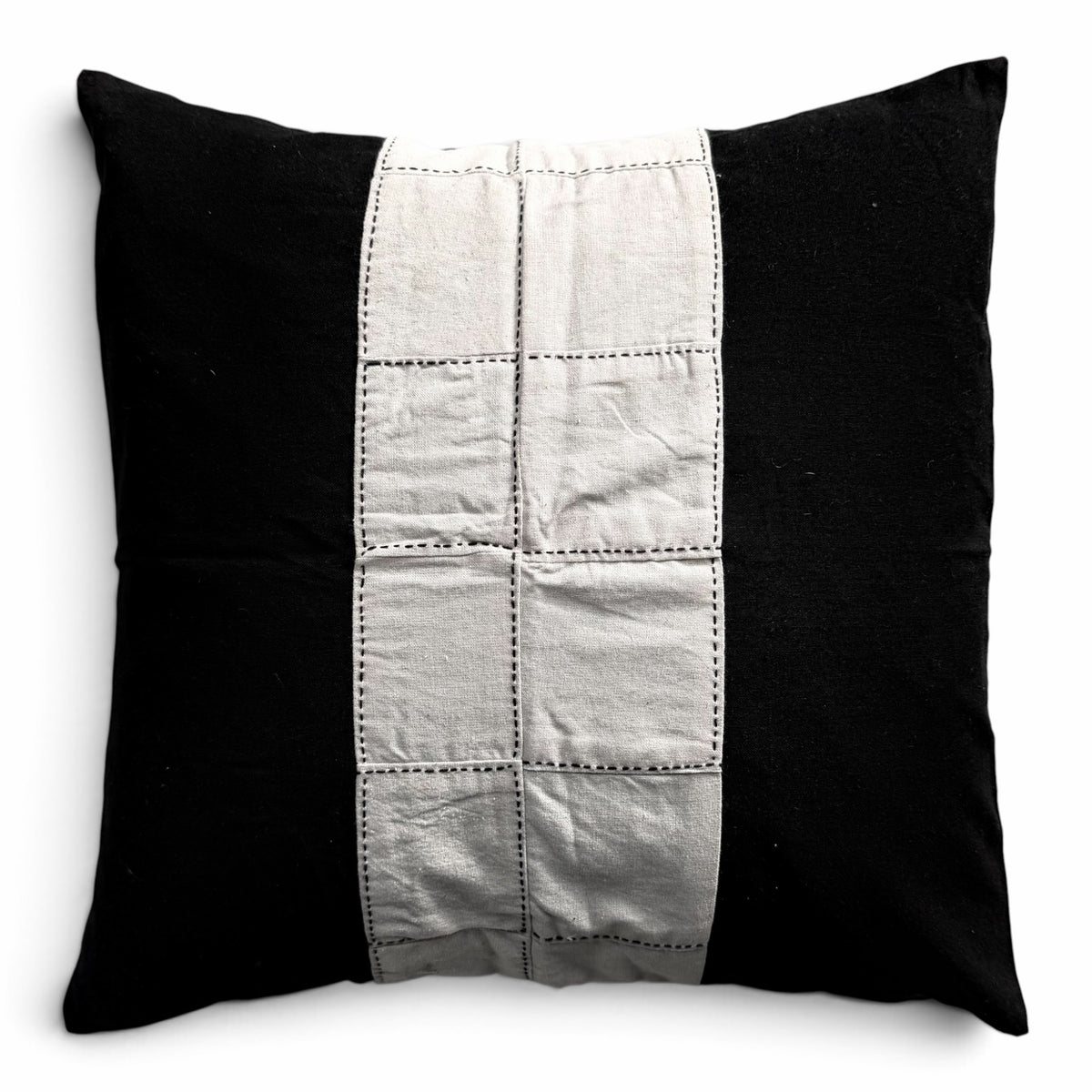 Håndlavet himmerli pyntepude i sort og beige med patchwork-panel og dekorative stikninger i et moderne design.