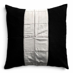 Håndlavet himmerli pyntepude i sort og beige med patchwork-panel og dekorative stikninger i et moderne design.